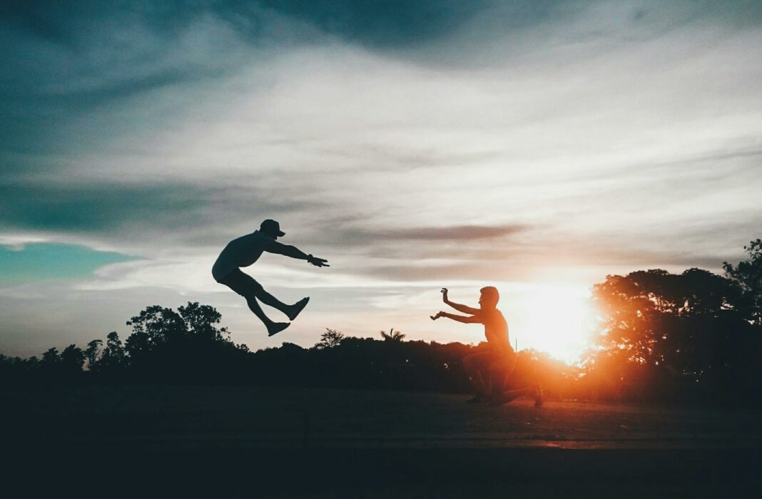 person in front of man flying wearing hat during sunset